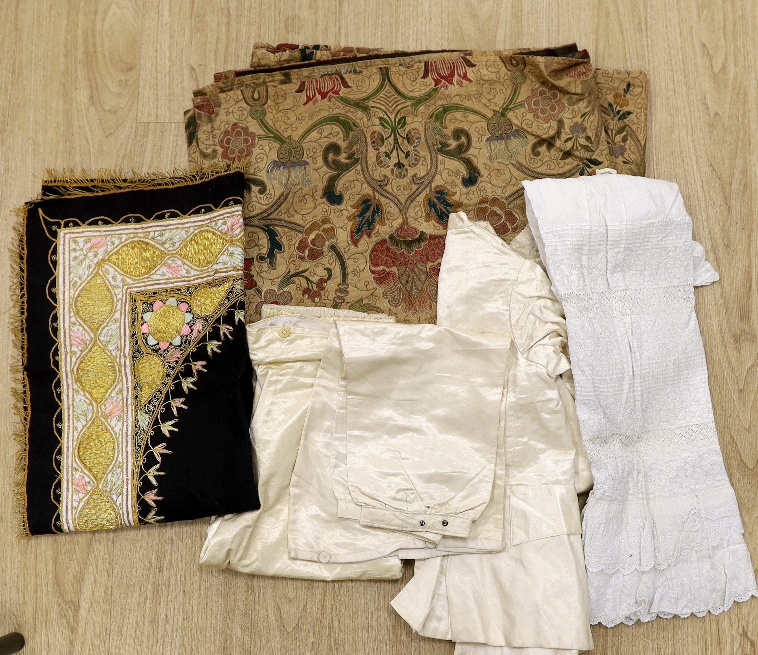 An embroidered Indian felt cover, a cream satin pageboy outfit, a white work christening gown, a silk shawl, a knitted silk shawl and a length of brocade